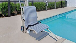 A poolside area with a lounge chair and a pool. - Baymont by Wyndham Sanford (Sanford)