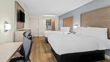 Een hotelkamer met twee bedden, een bureau, een stoel, een televisie en een raam met gordijnen.