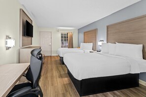 Habitación de hotel con dos camas, un escritorio, una silla, un televisor y una ventana con cortinas.