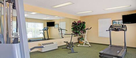 A fitness room with exercise equipment, a treadmill, and a large mirror.