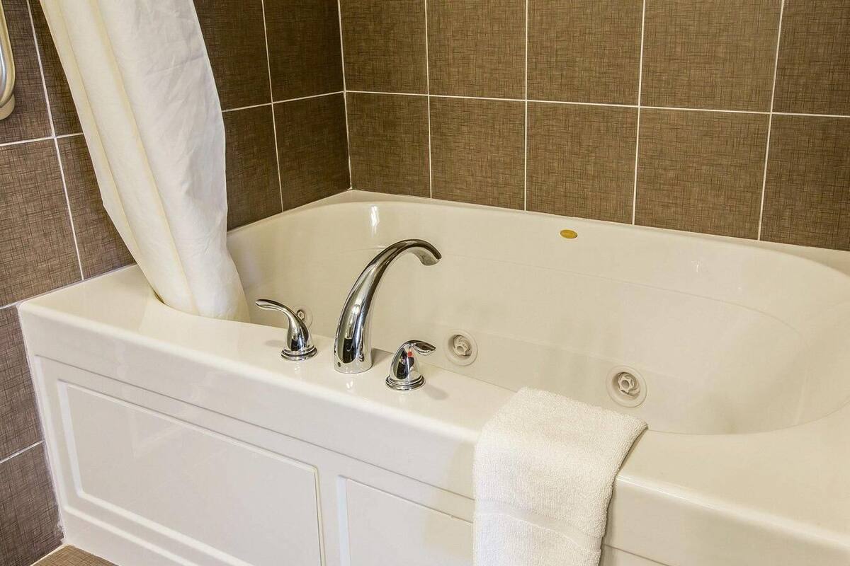 A white bathtub with two faucets and a towel on the side.