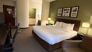 Ett hotellrum med en stor säng, ett skrivbord, en stol och en tv.