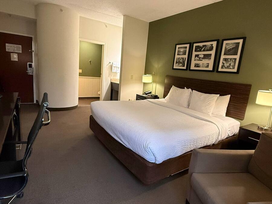 Ett hotellrum med en stor säng, ett skrivbord, en stol och en tv.
