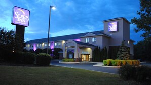 Un hotel Sleep Inn con un letrero llamativo, una entrada bien iluminada y un jardín frontal cuidado.