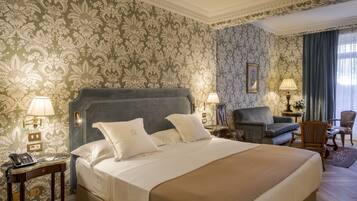 Une chambre d’hôtel bien aménagée, dotée d’un grand lit, de deux lampes de chevet, d’un téléphone et d’un coin salon avec un fauteuil et une petite table.