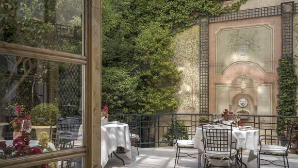 An outdoor patio with tables and chairs, surrounded by greenery and a decorative wall. - Relais & Châteaux Hotel Orfila (Madrid)