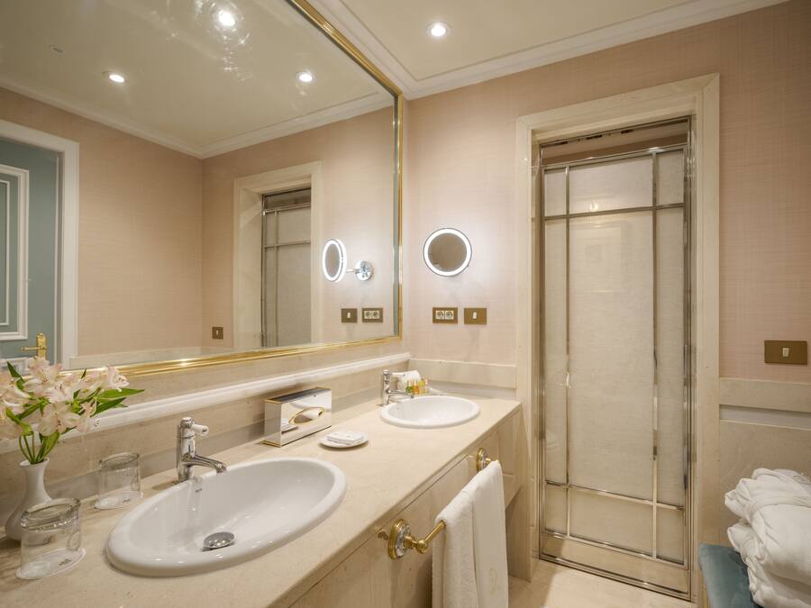 A bathroom with two sinks, a large mirror, and a glass shower enclosure.