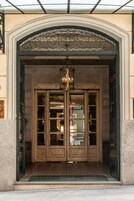Imponente entrada con una reja de hierro forjado, un candelabro y un juego de puertas dobles.