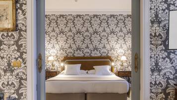 Une chambre à coucher avec un grand lit, un plancher en bois et un papier peint à motifs.