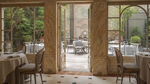 An elegant dining area with marble-paneled walls, large arched windows, and a view of the garden. - Relais & Châteaux Hotel Orfila (Madrid)