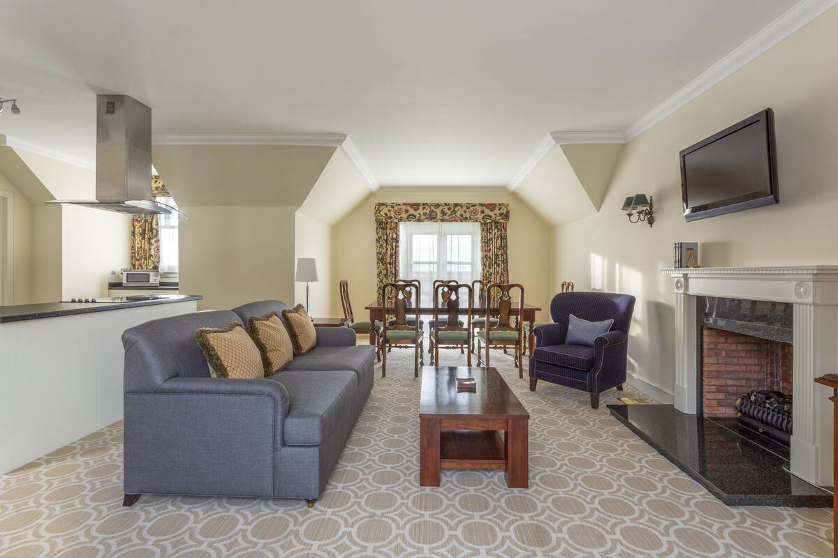 A living room with a sofa, coffee table, fireplace, dining area, and kitchen.
