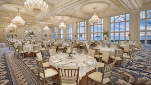 A large banquet hall with round tables, chandeliers, and a view of the sea. - Trump Turnberry (Girvan)