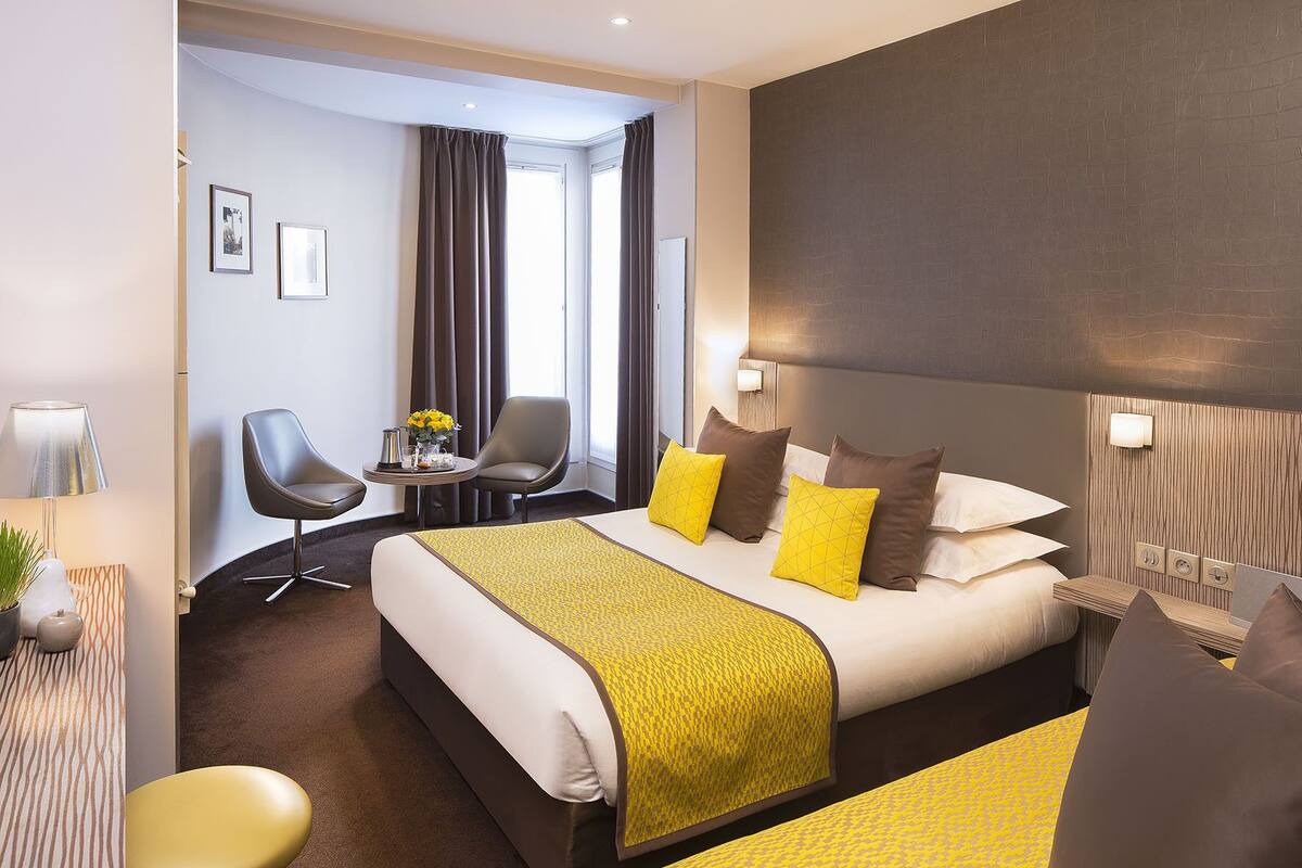 A hotel room with a large bed, a desk with a chair, and a view of the outdoors.