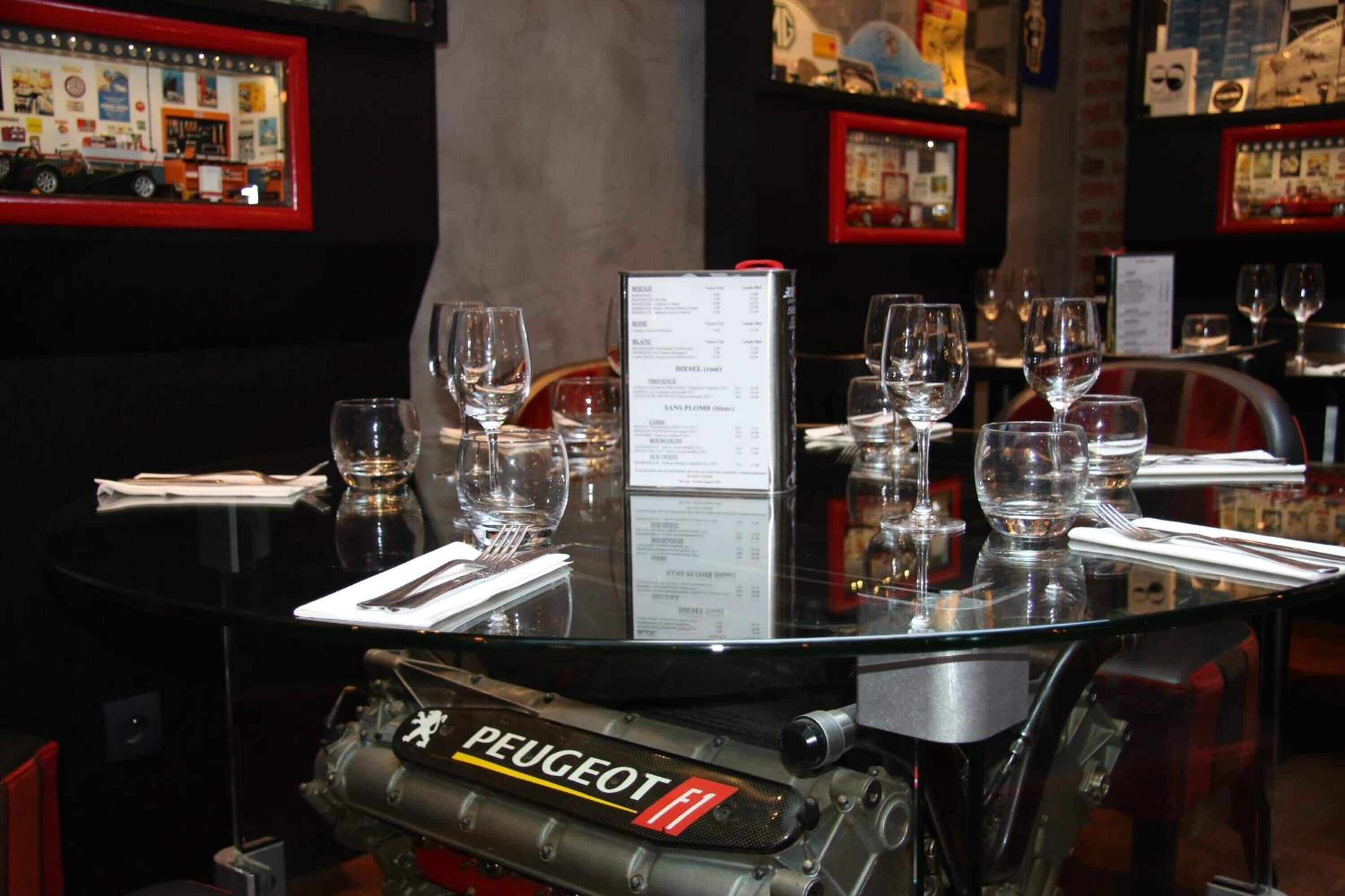 Ein Restauranttisch mit Speisekkarte, Gläsern und einem Modell eines Peugeot F1 Motors.