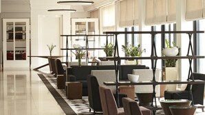 A modern hotel lobby with a long reception desk, comfortable seating areas, and large windows allowing natural light. - Hyatt Regency Bishkek (Bishkek)