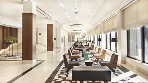 A spacious hotel lobby with a long reception desk, comfortable seating, and large windows. - Hyatt Regency Bishkek (Bishkek)