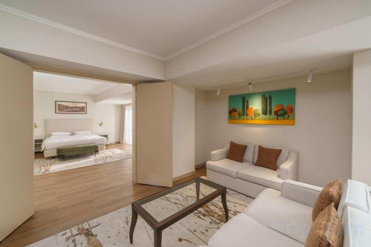 A modern living room with a sofa, coffee table, and a painting on the wall.