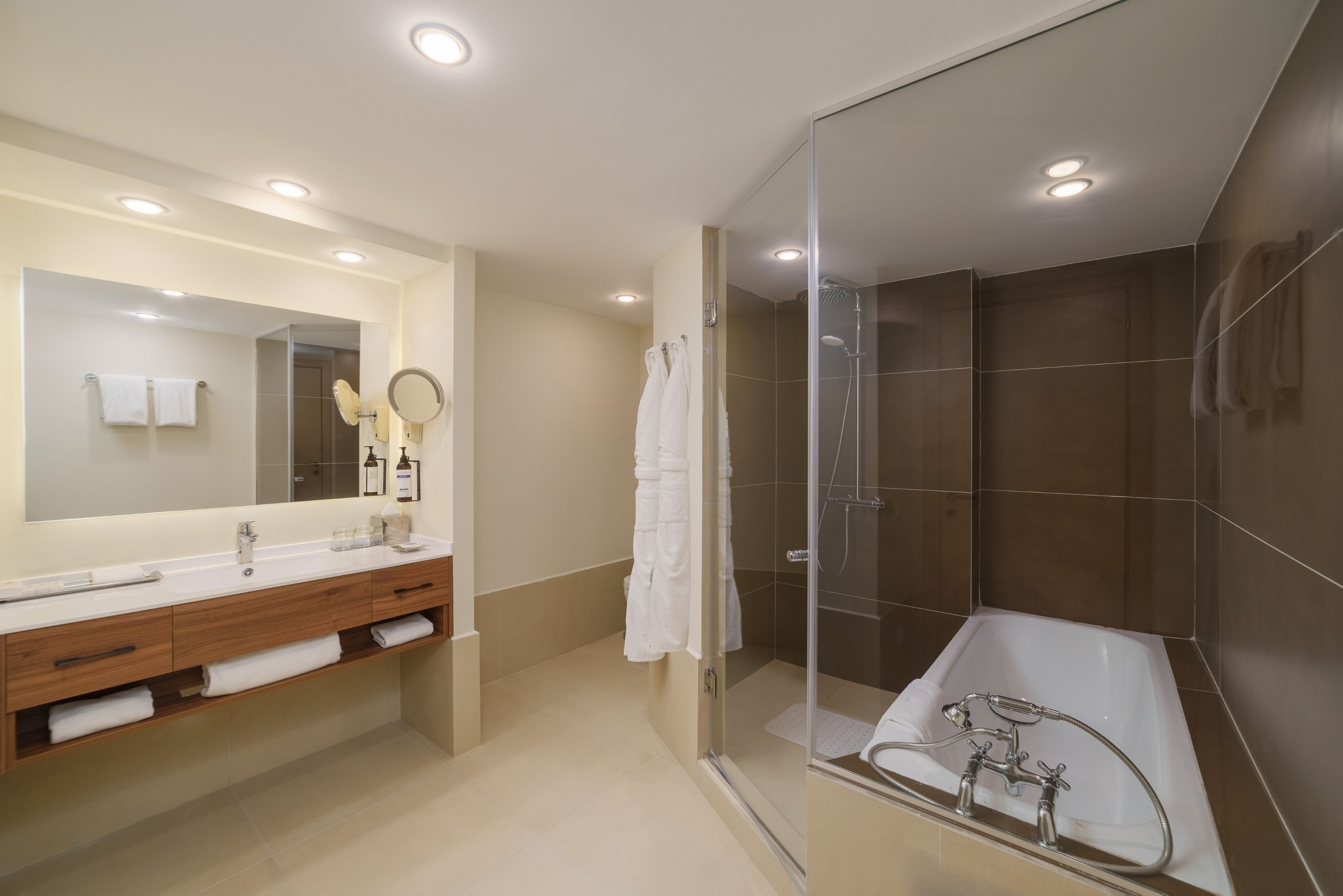 A modern bathroom with a glass-enclosed shower, a large mirror, and a bathtub.