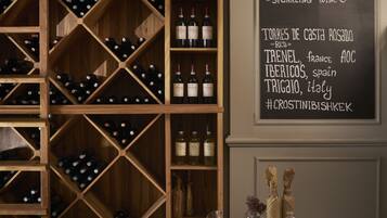 A wine cellar with wooden shelves and a chalkboard menu listing wine varieties and prices.