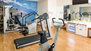 Un gimnasio con equipo de cardio, cinta de correr y bicicleta estática.