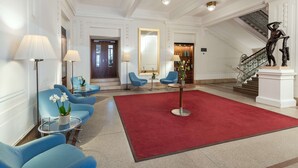Un vestíbulo con sillas azules, una alfombra roja y una escalera.