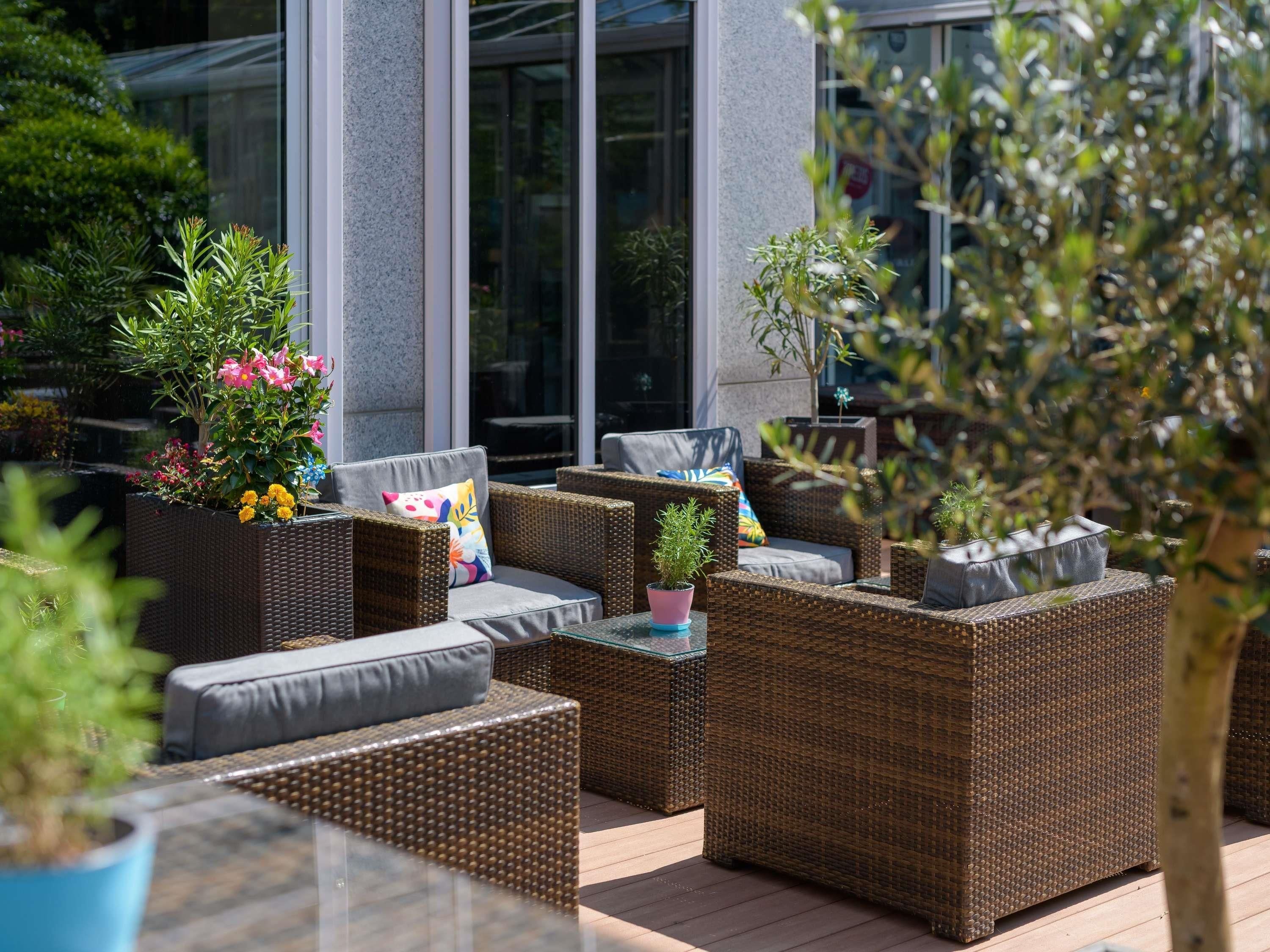 An outdoor seating area with wicker furniture and potted plants.
