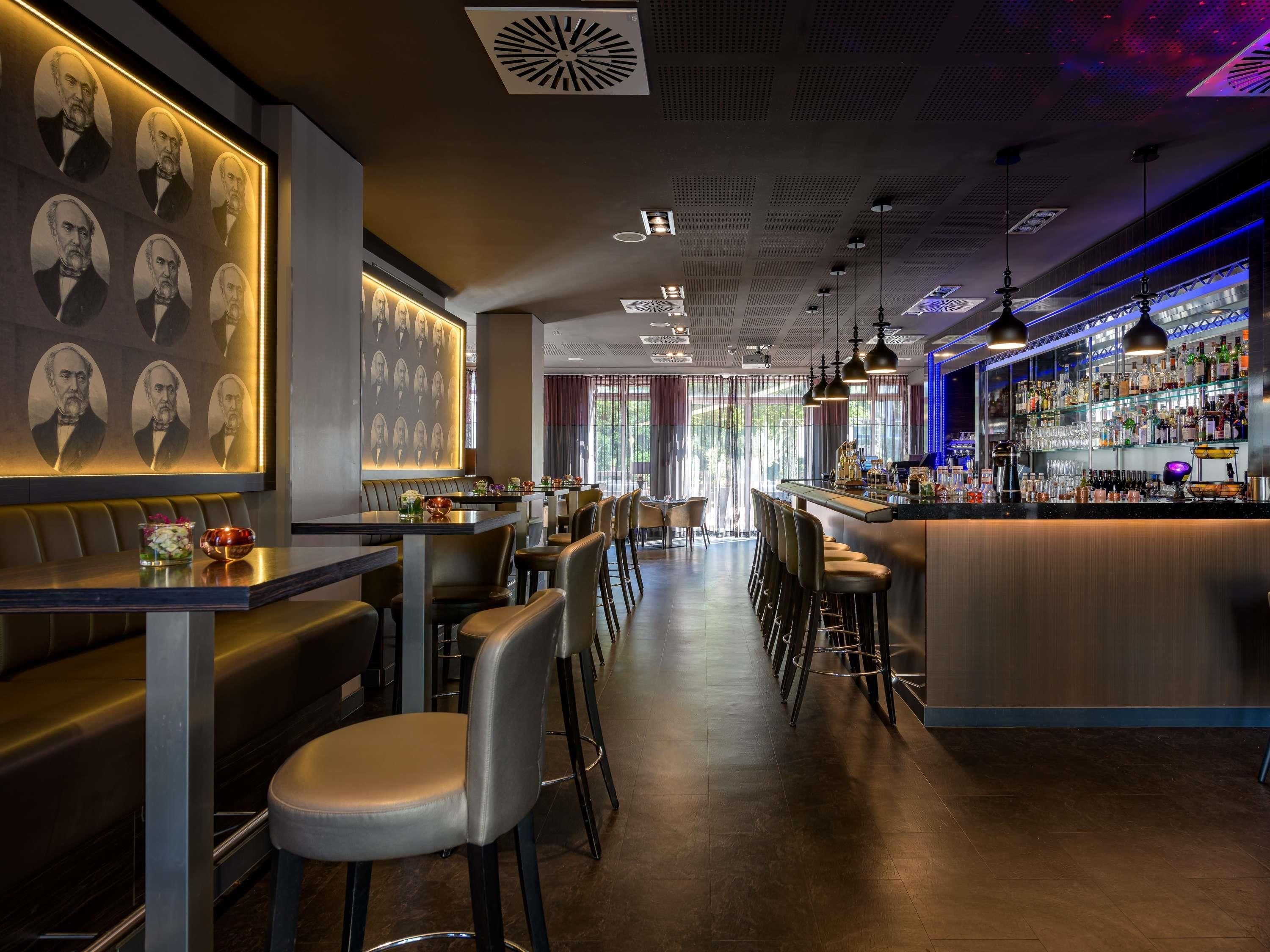 Eine Bar mit Sitzgelegenheiten, einer Theke und einer Wand mit gerahmten Portraits.