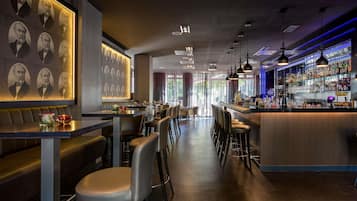 Eine Bar mit Sitzgelegenheiten, einer Theke und einer Wand mit gerahmten Portraits.