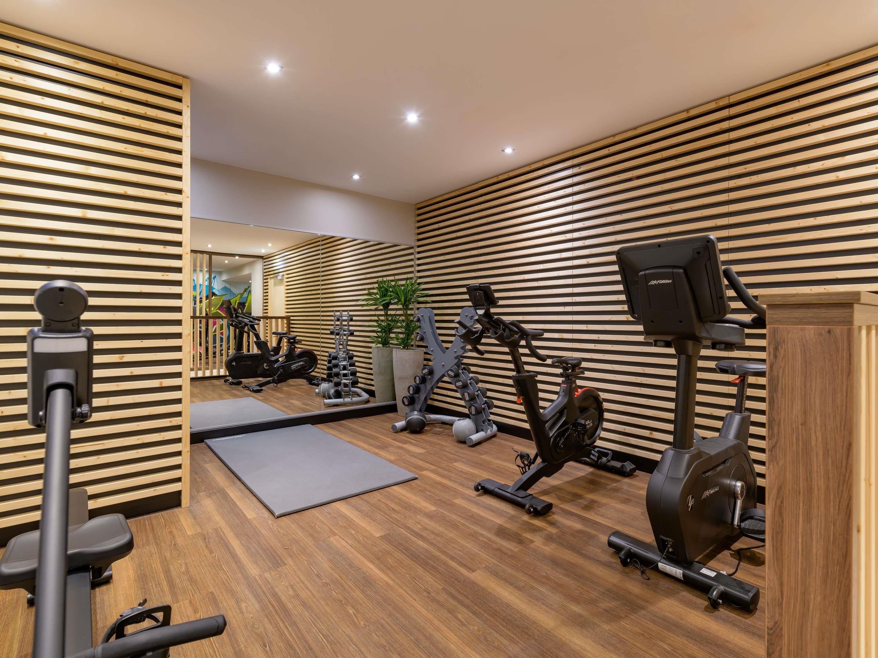 A gym with wooden slat walls, exercise equipment, and a mirror.