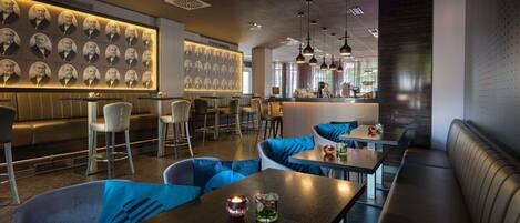Un interior de restaurante moderno con una zona de bar, asientos y una pared con diseño.