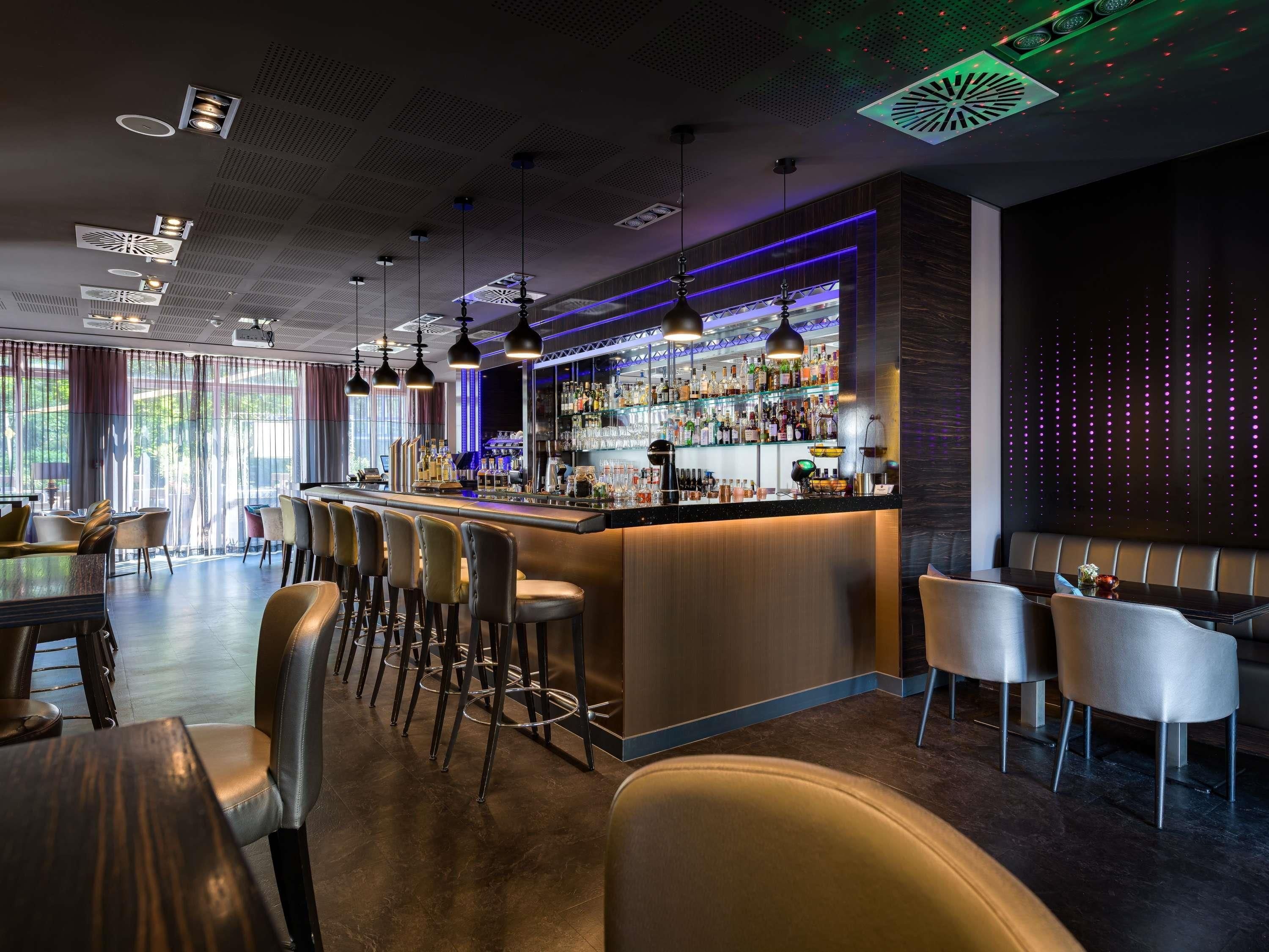 A bar area with a counter, stools, and a seating area with tables and chairs.