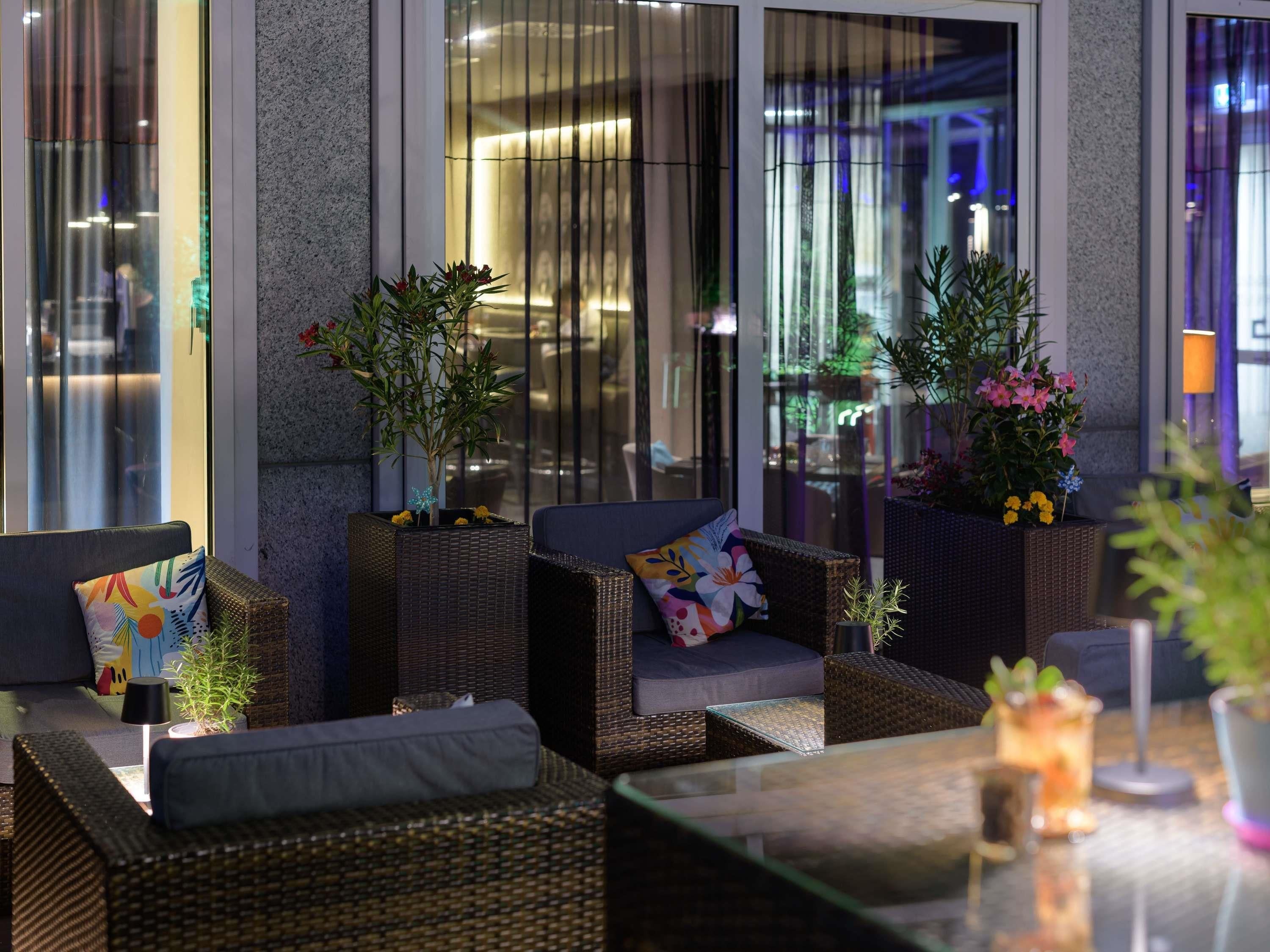 An outdoor seating area with wicker furniture and potted plants.