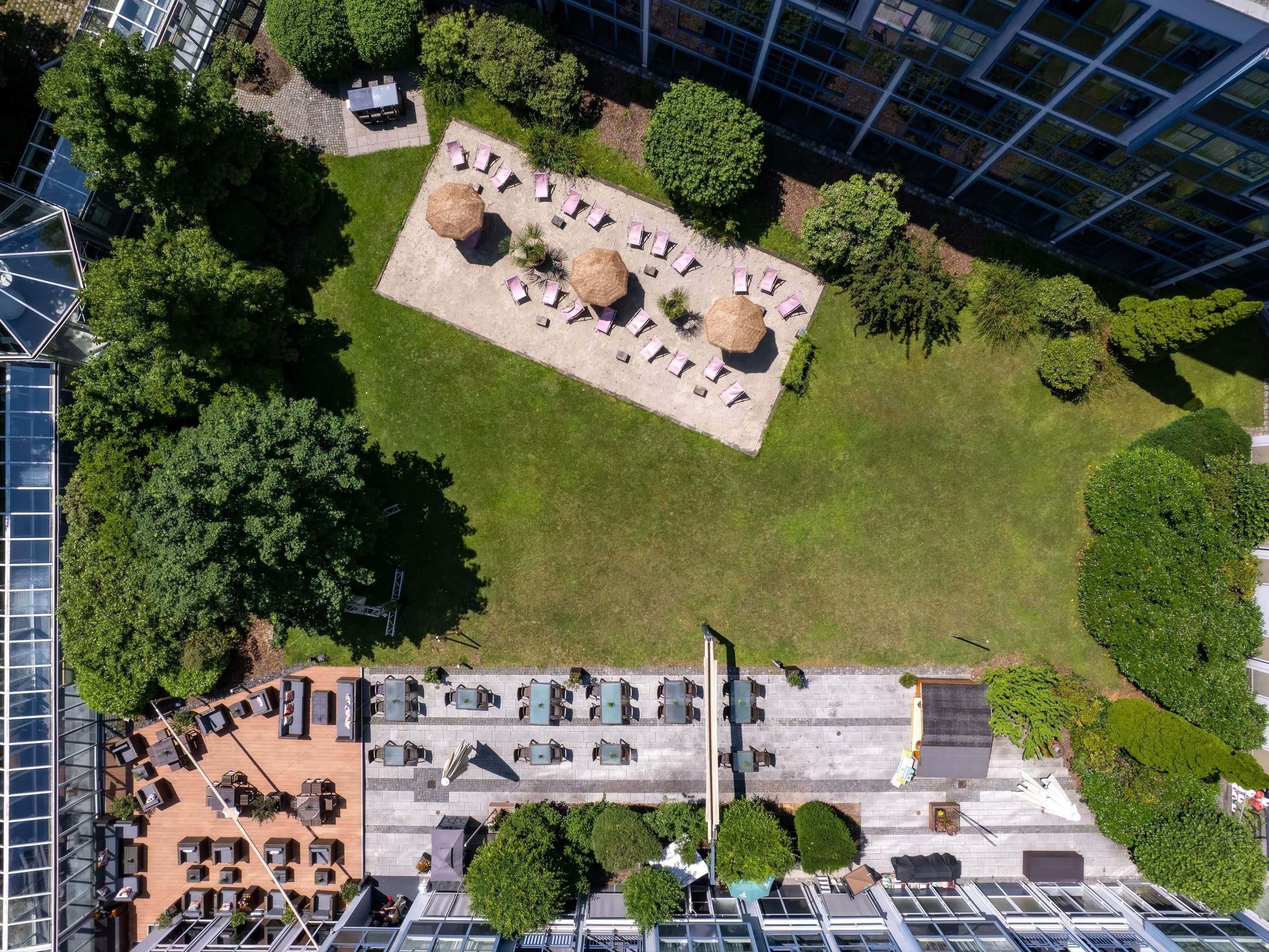 An aerial view of a rooftop garden with seating areas, surrounded by modern buildings.