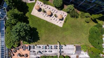 An aerial view of a rooftop garden with seating areas, surrounded by modern buildings.