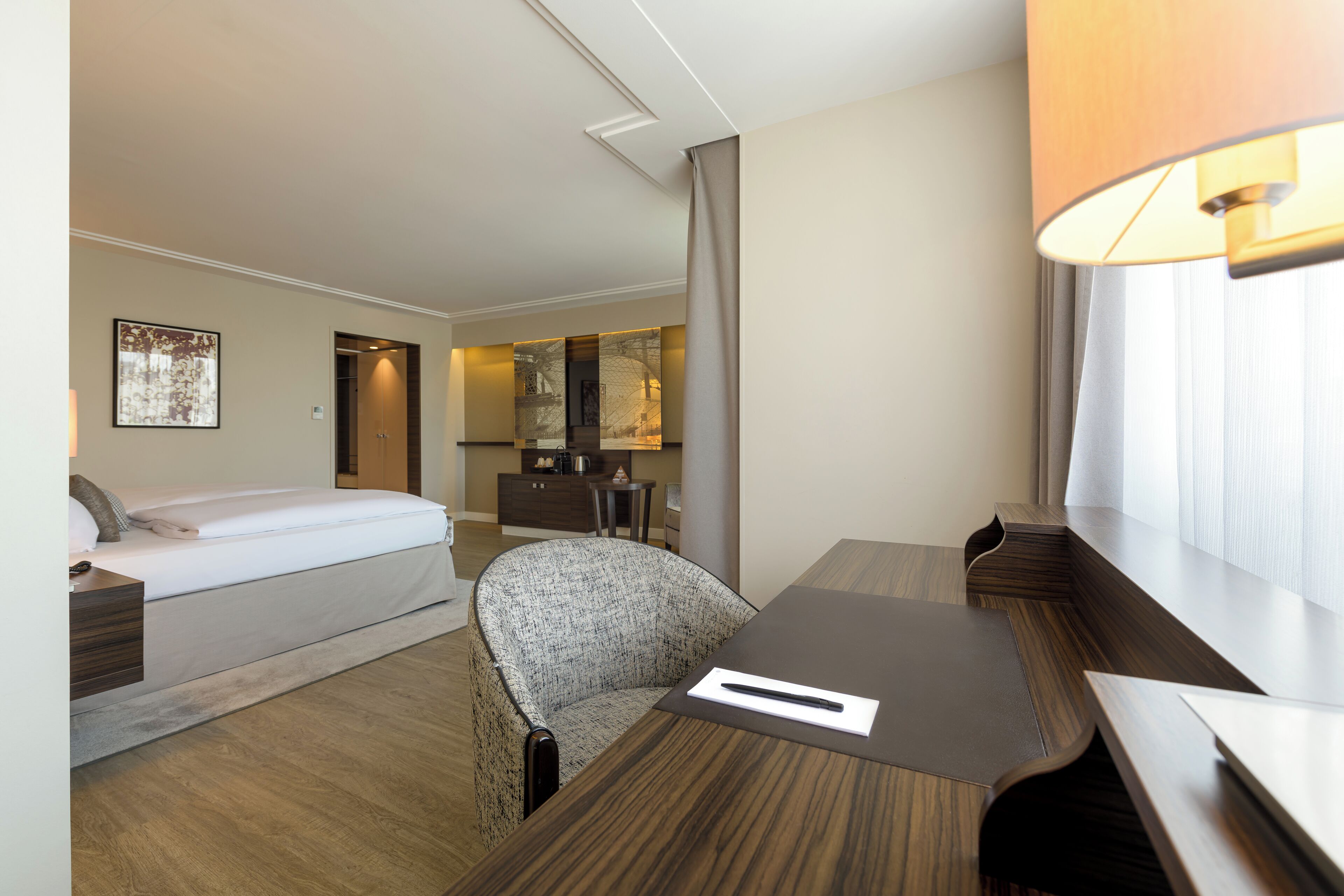 Ein Hotelzimmer mit Bett, Schreibtisch, Stuhl, Lampe und Blick auf den Speisesaal.