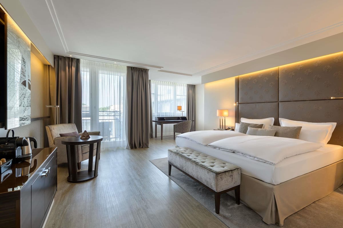 Habitación de hotel moderna con una cama grande, un escritorio, una silla y vistas al exterior.