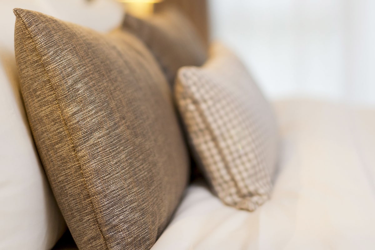A bed with multiple pillows and a bedside lamp.