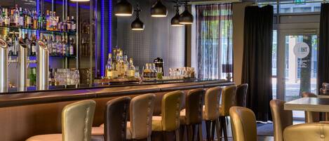 A bar area with multiple stools, a bar counter stocked with bottles, and hanging pendant lights.