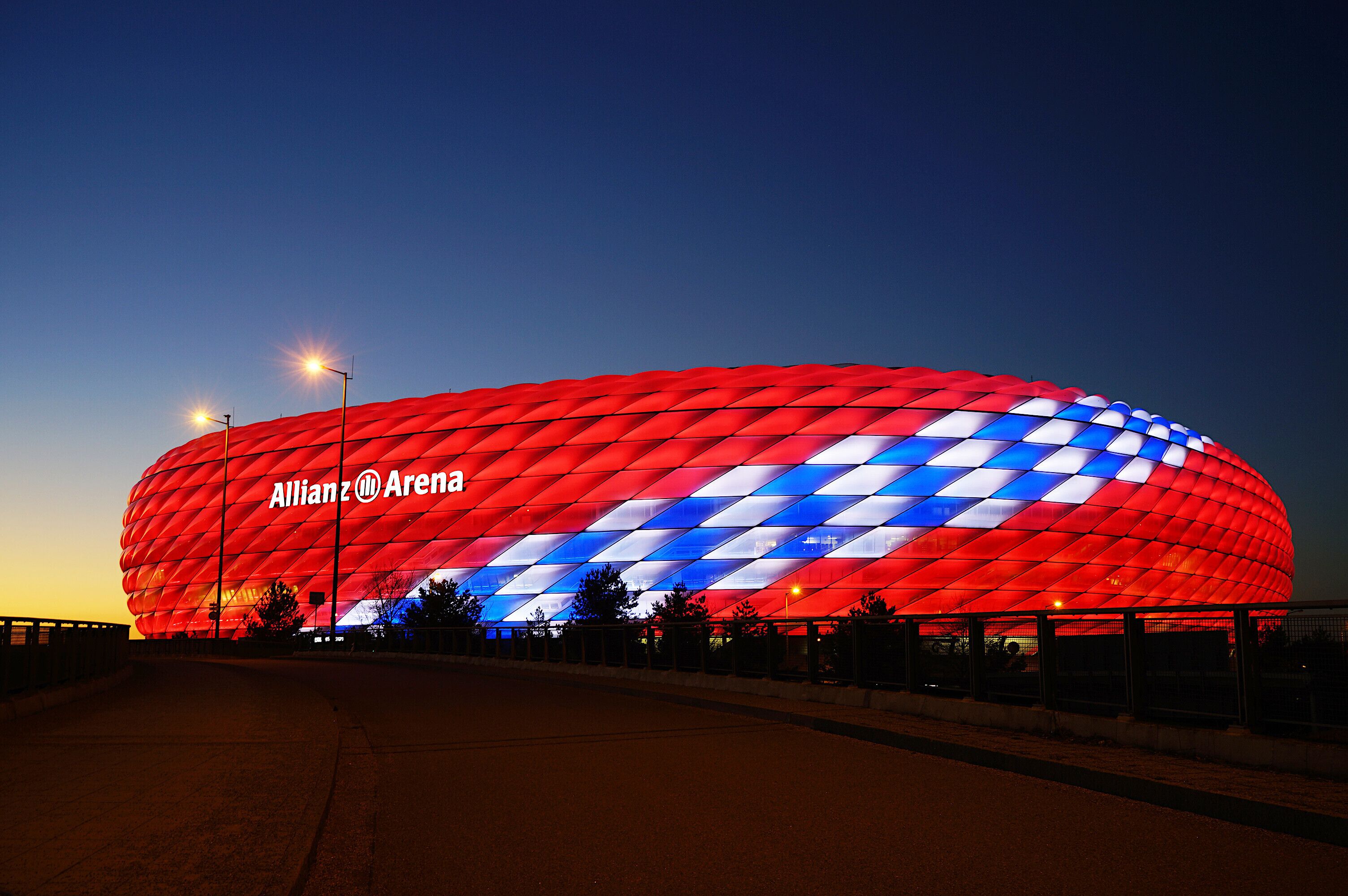 Un estadio grande, iluminado en rojo y azul, con el nombre Allianz Arena a la vista.
