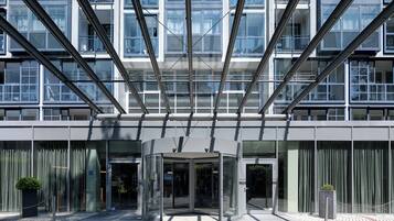 A modern building with a glass entrance, metal framework, and a potted plant.