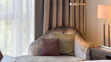 A modern hotel room with a curved sofa, a bedside table, and a lamp.