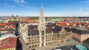 A historic building with a prominent tower and intricate architecture, surrounded by a cityscape with red-roofed buildings. - Pullman Munich (Munich)
