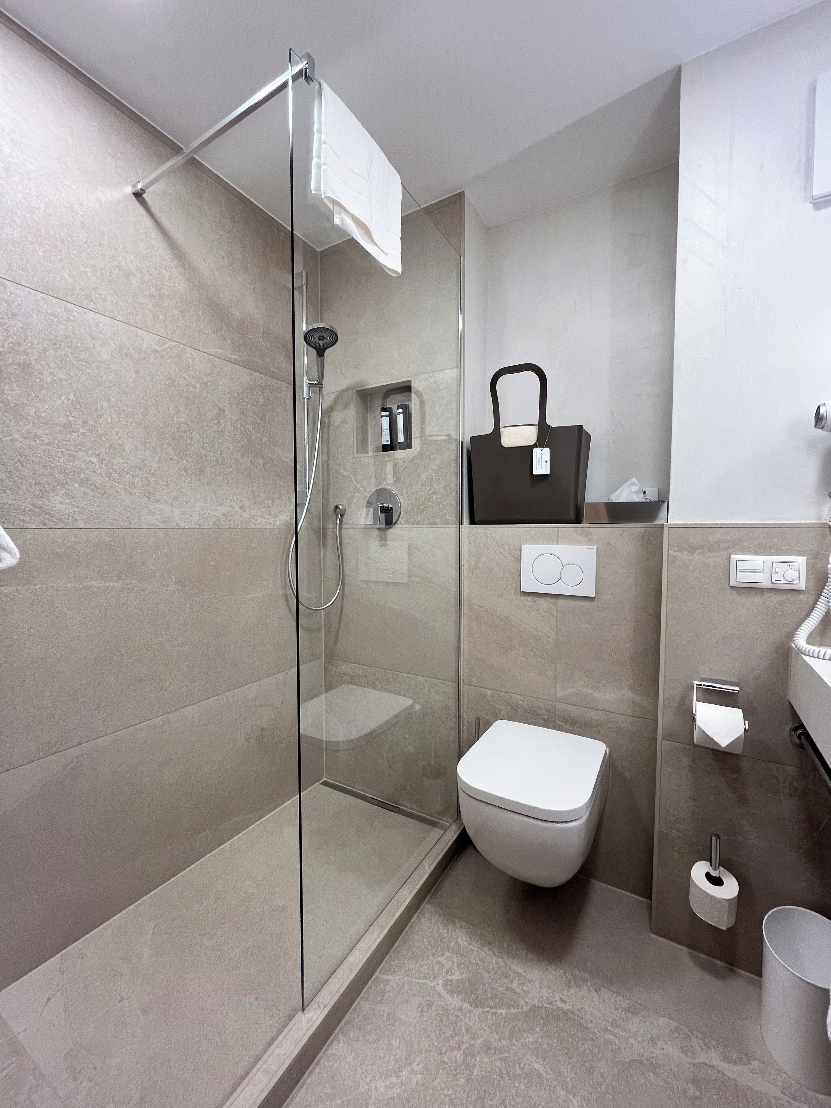 Et moderne badeværelse med bruseniche, toilet og håndvask.