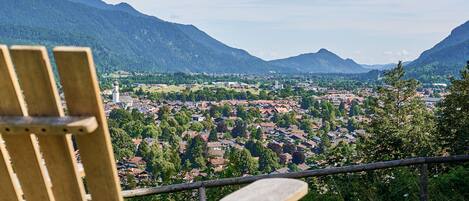 A wooden chair overlooking a town with mountains in the background.