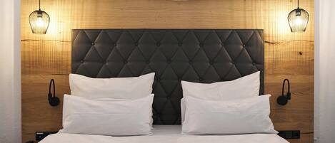 Una cama con cabecera capitonada, dos mesitas de noche y dos lámparas de pared.