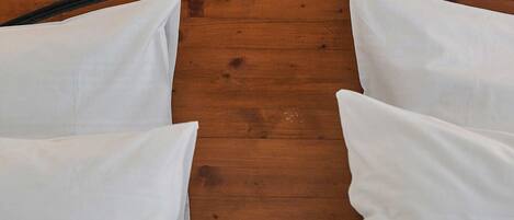A neatly made bed with a wooden headboard and white linens.