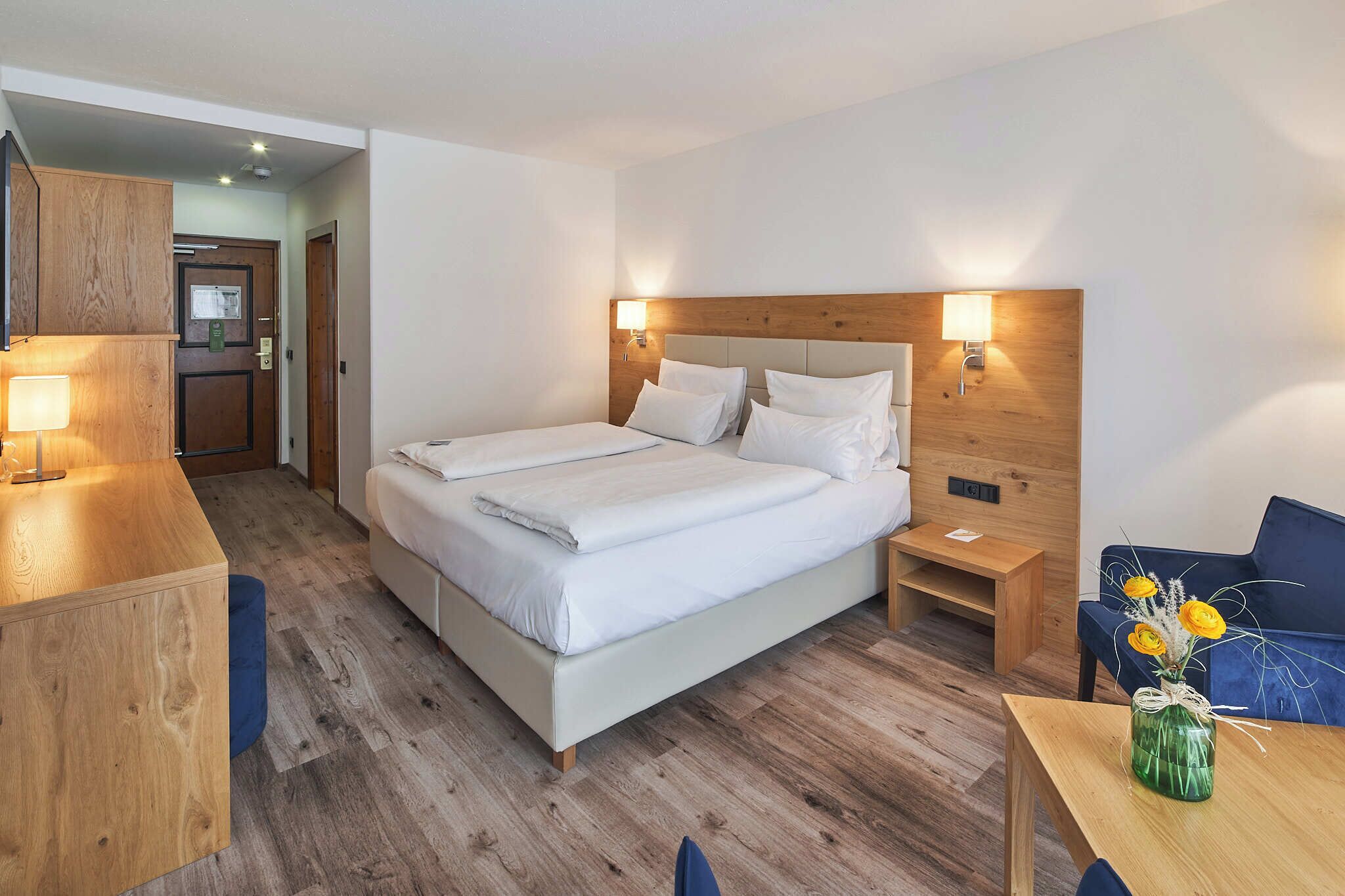 Ein Hotelzimmer mit einem großen Bett, Nachttischen, einem Schreibtisch und einem Stuhl.