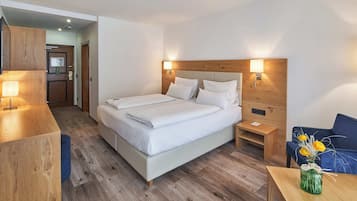 A hotel room with a large bed, bedside tables, a desk, and a chair.