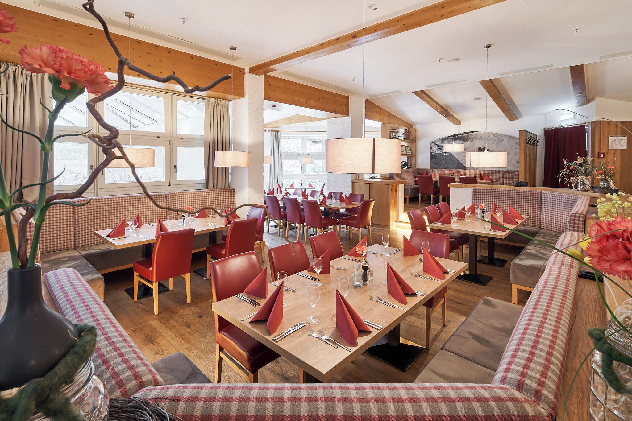 Un restaurante con asientos a cuadros, vigas de madera y grandes ventanales.