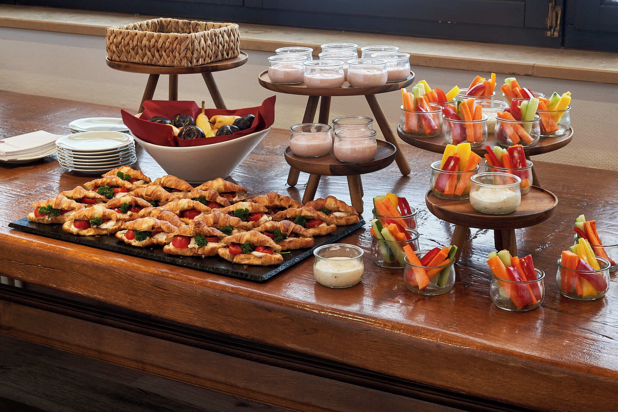 Una mesa de buffet con cruasanes, copas de fruta y diversas salsas.